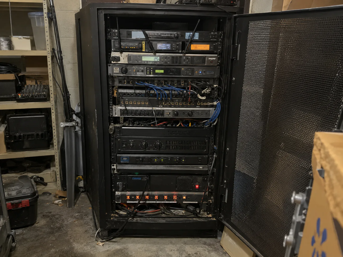 Ageing hall sound system equipment rack with the cabinet door open